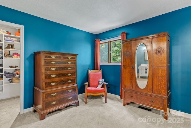 living area featuring a textured ceiling, carpet flooring, visible vents, and baseboards