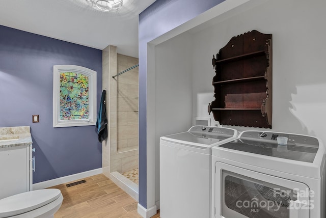 laundry area featuring laundry area, visible vents, baseboards, independent washer and dryer, and wood finish floors