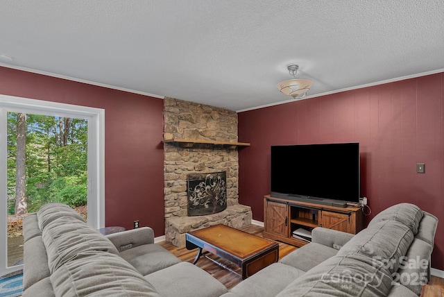 living room featuring a textured ceiling, ornamental molding, a fireplace, and wood finished floors