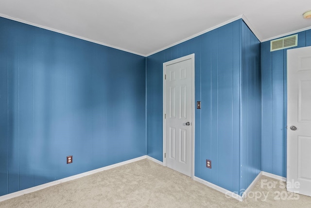 carpeted empty room with visible vents, crown molding, and baseboards