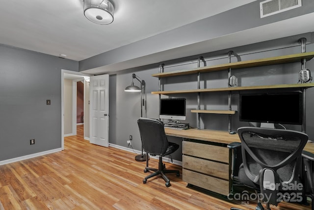 office area featuring light wood-type flooring, visible vents, and baseboards