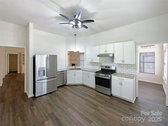 kitchen featuring stainless steel appliances, light countertops, white cabinetry, a sink, and under cabinet range hood