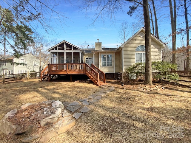 rear view of property with a sunroom, a chimney, fence, and stairway