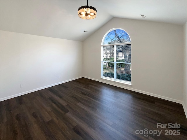 additional living space with dark wood-style floors, a notable chandelier, lofted ceiling, and baseboards