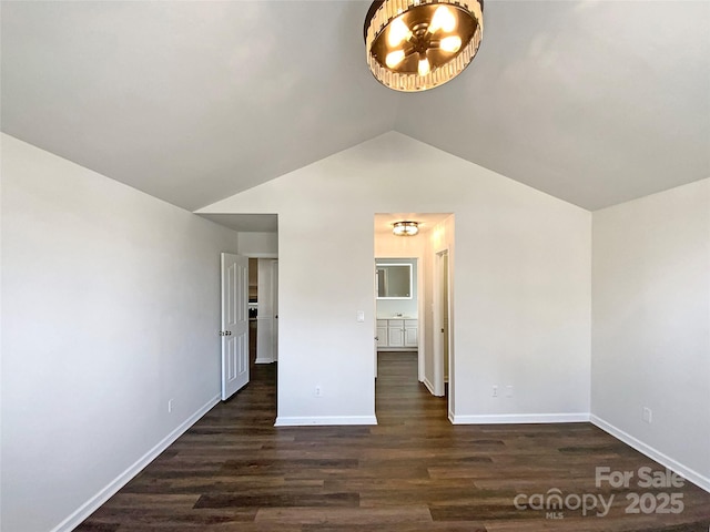 spare room with dark wood-style floors, lofted ceiling, and baseboards