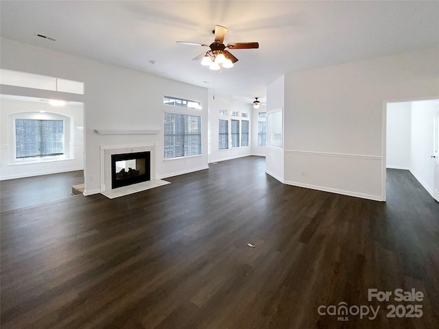 unfurnished living room with dark wood-style floors, baseboards, and a multi sided fireplace