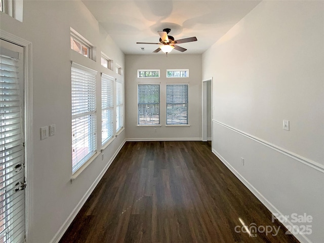 unfurnished room featuring dark wood-type flooring, ceiling fan, and baseboards