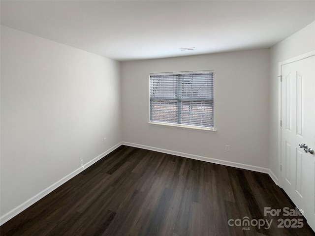 spare room with visible vents, baseboards, and dark wood-style flooring