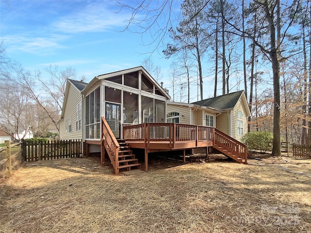 rear view of house with a sunroom, fence, stairway, and a wooden deck