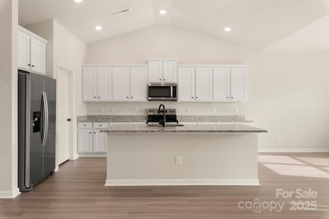 kitchen featuring light stone countertops, a kitchen island with sink, stainless steel appliances, light wood-style floors, and white cabinetry