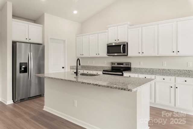 kitchen featuring lofted ceiling, appliances with stainless steel finishes, white cabinets, and a sink