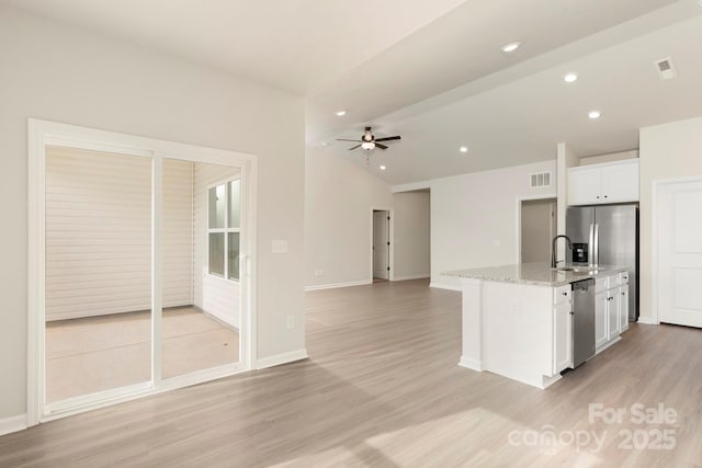 kitchen featuring visible vents, white cabinets, appliances with stainless steel finishes, vaulted ceiling, and light wood-type flooring