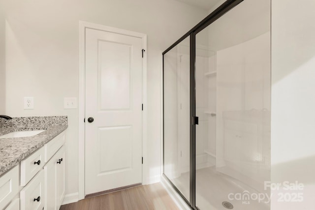 full bathroom featuring a stall shower, wood finished floors, and vanity