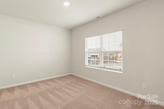 spare room with carpet floors, visible vents, and baseboards