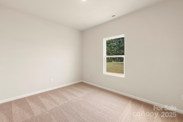 empty room featuring light colored carpet, visible vents, and baseboards