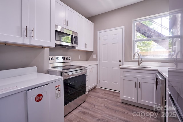 kitchen featuring stainless steel appliances, light countertops, light wood-style floors, white cabinetry, and a sink