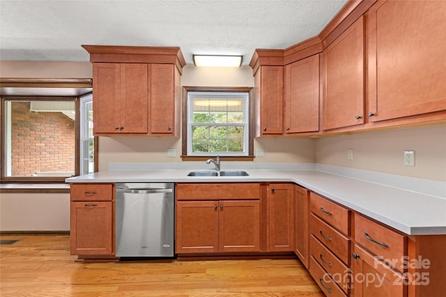 kitchen with light countertops, dishwasher, light wood-style flooring, and a sink