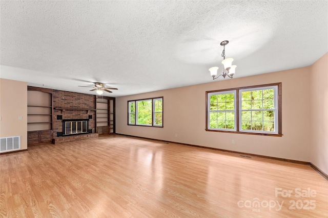 unfurnished living room featuring a brick fireplace, light wood-style flooring, visible vents, and a textured ceiling