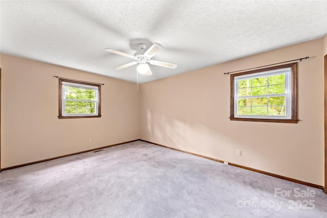 carpeted spare room with a textured ceiling and baseboards