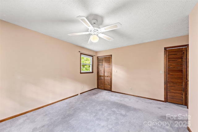 carpeted empty room featuring ceiling fan, baseboards, and a textured ceiling