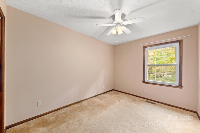 empty room featuring a textured ceiling, baseboards, visible vents, and light colored carpet