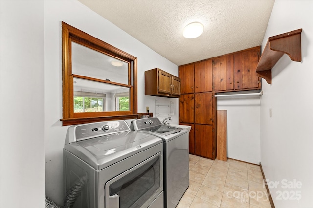 laundry area with cabinet space, independent washer and dryer, a textured ceiling, and light tile patterned floors