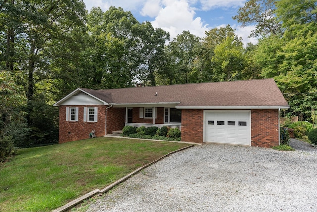 single story home with gravel driveway, brick siding, covered porch, an attached garage, and a front yard