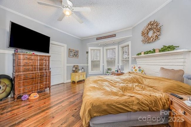 bedroom with a textured ceiling, a ceiling fan, wood finished floors, and ornamental molding