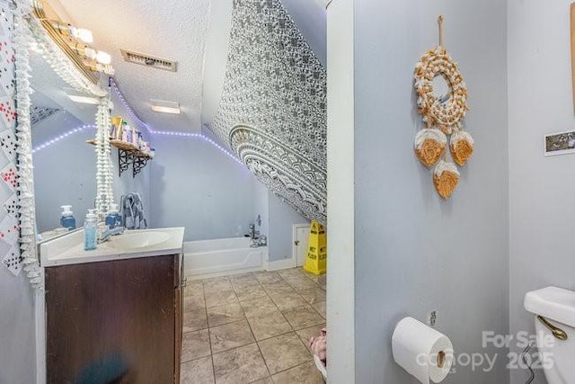 bathroom featuring vanity, a bath, visible vents, a textured ceiling, and toilet