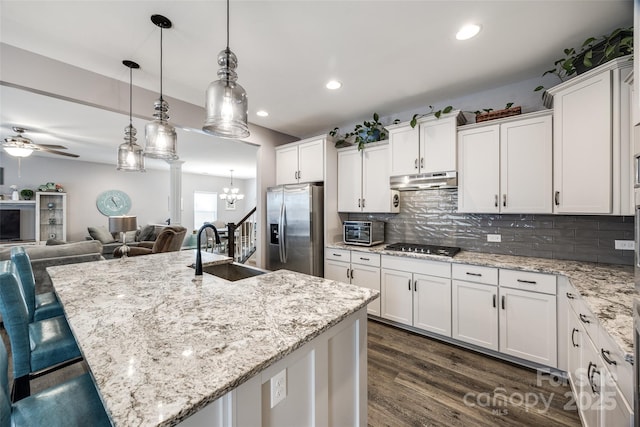 kitchen featuring stainless steel appliances, a sink, white cabinetry, and under cabinet range hood