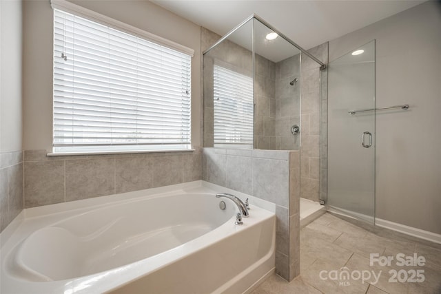 full bath with a stall shower, tile patterned floors, and a bath