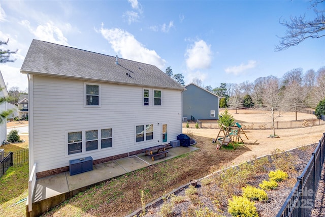 rear view of house featuring roof with shingles, a patio area, and a fenced backyard