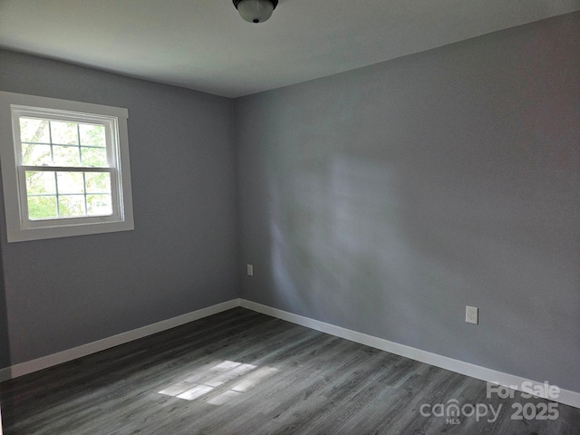 unfurnished room featuring dark wood-style flooring and baseboards