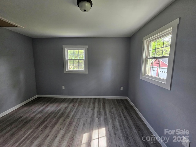 spare room featuring dark wood-style floors, plenty of natural light, and baseboards