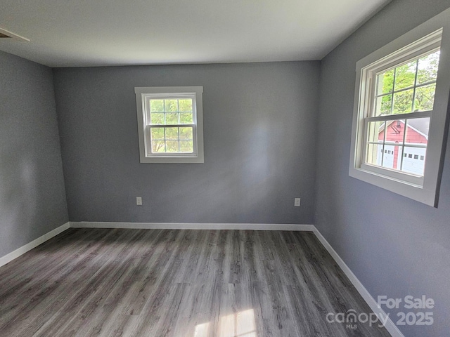 spare room with dark wood-type flooring and baseboards