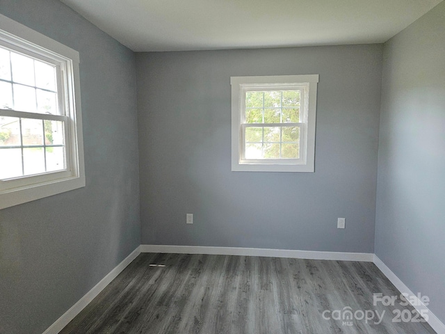 unfurnished room featuring baseboards and dark wood finished floors