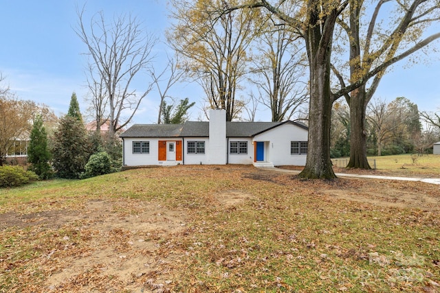 single story home featuring a chimney and a front lawn