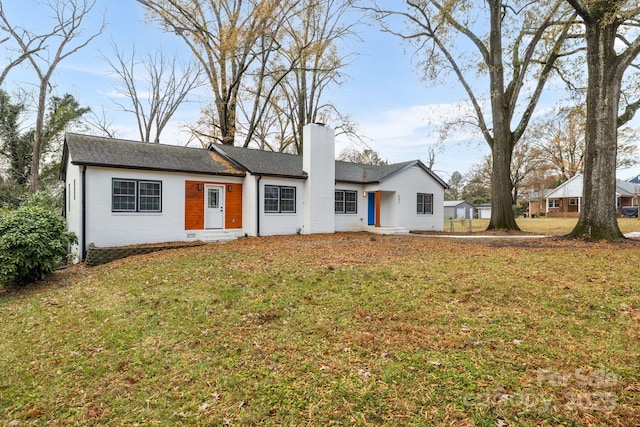 single story home with a front yard, a chimney, and brick siding