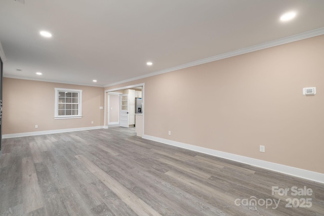 spare room with crown molding, wood finished floors, and baseboards