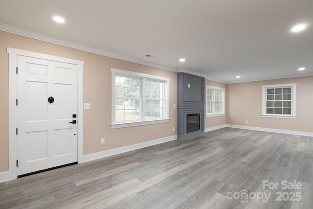 unfurnished living room with a large fireplace, baseboards, crown molding, and wood finished floors