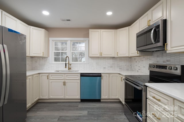 kitchen with visible vents, decorative backsplash, dark wood-style floors, stainless steel appliances, and a sink