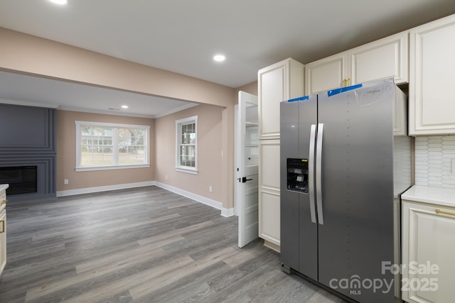 kitchen featuring baseboards, white cabinets, light wood-style floors, a fireplace, and stainless steel refrigerator with ice dispenser