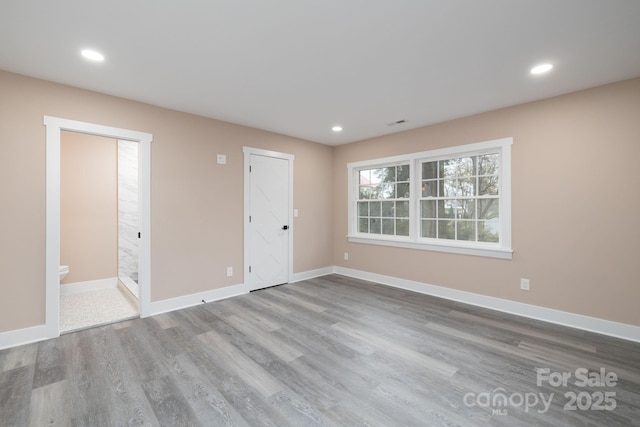 empty room featuring recessed lighting, baseboards, and wood finished floors