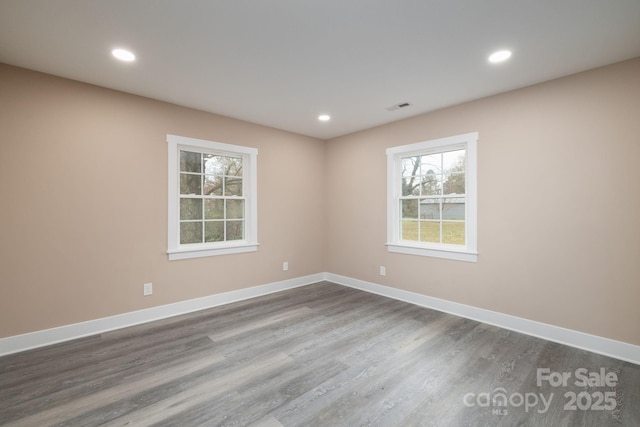 empty room with recessed lighting, dark wood finished floors, visible vents, and baseboards