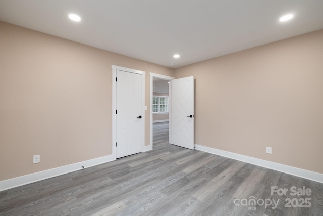 spare room with recessed lighting, wood finished floors, and baseboards