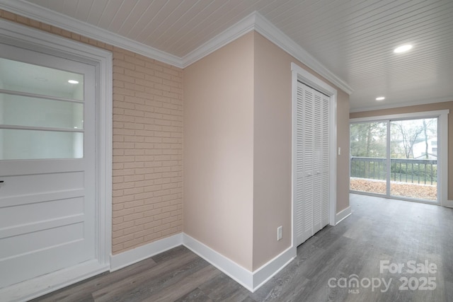 hall featuring dark wood-style floors, brick wall, baseboards, and crown molding