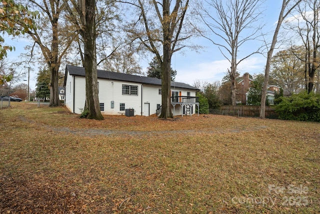 rear view of property with a lawn and cooling unit