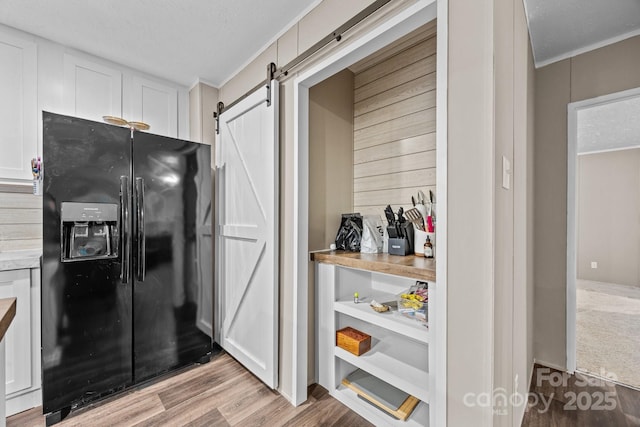 11 Pyrite Way, Asheville, NC 28806 - kitchen featuring black fridge, a barn door, light wood-style floors, ornamental molding, and white cabinets