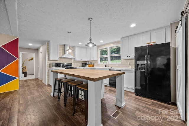 11 Pyrite Way, Asheville, NC 28806 - kitchen featuring black appliances, wall chimney exhaust hood, wood counters, a kitchen breakfast bar, and white cabinetry