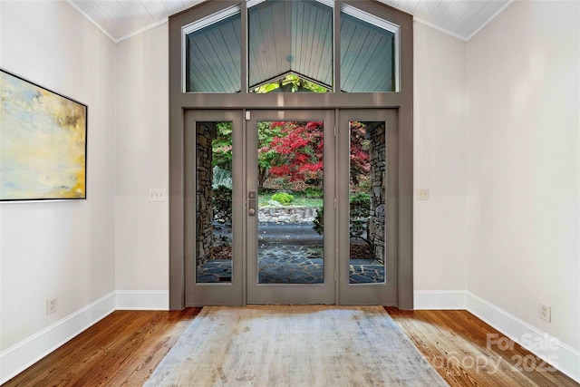 foyer featuring ornamental molding, vaulted ceiling, baseboards, and wood finished floors